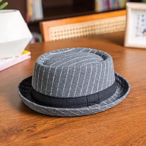Detailed view of grey pinstripe vintage pork pie hat on a cozy wooden table background
