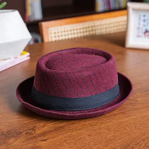Classic burgundy striped wool pork pie hat with black ribbon on a wooden table