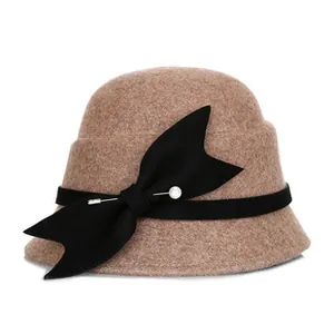 Detail of camel wool cloche hat featuring black grosgrain ribbon and pearl bow ornament