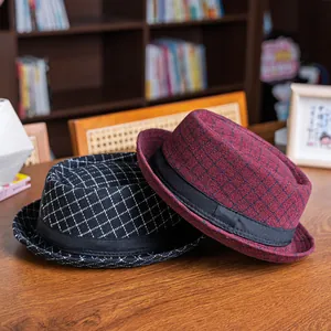 Detail view of retro plaid wool fedora hats in black and burgundy on a wooden surface