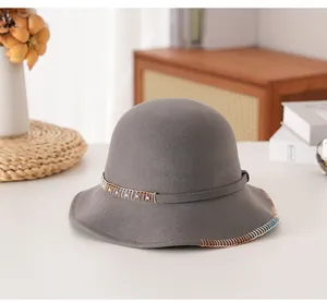 Dettaglio cappello cloche in lana grigio scuro con cuciture colorate e metallo