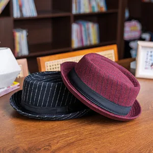 Detailed texture of retro plaid fedora hats in black and burgundy on a wooden desk