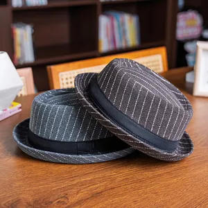 Detail of dark grey and coffee pinstripe fedora hats with black ribbon on a wooden desk