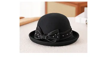 Dettaglio di un cappello elegante in feltro di lana nero con fiocco di raso e perle