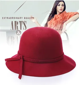 Close-up of a red wool cloche hat featuring a decorative ribbon and elegant side knot