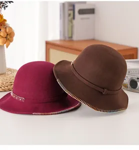 Dettaglio di cappelli cloche in lana con cuciture metalliche in bordeaux e marrone