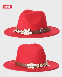 Dettaglio del cappello fedora in lana rossa con fascia in cuoio e fiori bianchi