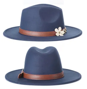 Dettaglio della fascia in ecopelle marrone con fiori bianchi su un cappello fedora blu