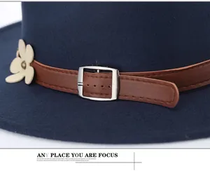 Dettaglio cappello fedora blu navy con fascia in pelle marrone e ciondolo a fiore