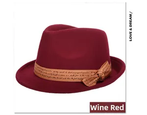 Detail of a wine red wool fedora hat featuring a khaki ribbon with elegant cursive lettering
