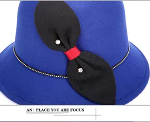 Dettaglio cappello in lana blu reale con fiocco di strass e catena di perle dorate