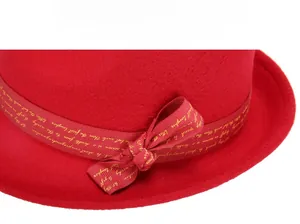 Detail of red wool felt fedora featuring a silk ribbon with gold script and a bow