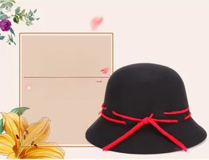 Close-up of elegant black wool felt dome hat with a contrasting red ribbon bow detail