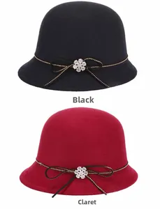 Detail of wool cloche hats with decorative rhinestone flowers and ribbons in black and claret
