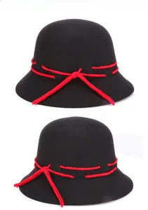 Close-up of black wool cloche hat featuring a bright red ribbon bow detail and dome top