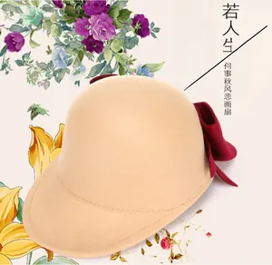 Detail of beige felt equestrian hat featuring a contrasting deep red bow decoration