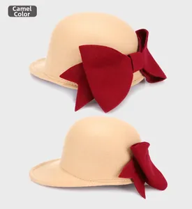 Close-up of elegant camel wool fedora hat featuring a large red decorative bow tie