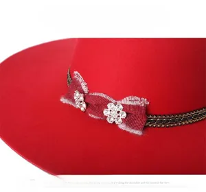 Detail of red wool felt fedora with textured bow and sparkling crystal flower accents