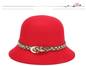 Dettaglio di cappello in feltro di lana rossa con nastro intrecciato e fibbia dorata