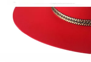 Detail of red wool fedora hat featuring intricate black and gold woven decorative band