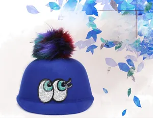 Detail of blue wool felt hat with colorful faux fur pompom and sequined eye embroidery
