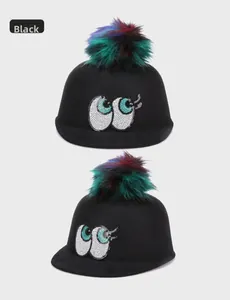 Detail of black wool felt hat with sequined eyes and colorful faux fur pom-poms