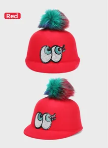 Detail of red wool felt hat with sequin eyes and colorful faux fur pom-pom topper