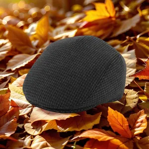 Close-up of winter flat cap with waffle knit texture on warm autumn maple leaves background