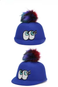 Detail view of royal blue wool felt hat with sequin eyes and colorful faux fur pom-pom