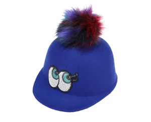 Close-up of royal blue wool hat with colorful pom-poms and cartoon eye sequin embroidery