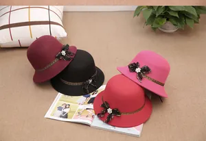 Detail view of colorful wool felt cloche hats with lace bows and rhinestone flowers
