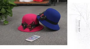 Détail de chapeau cloche en laine avec nœud en maille noire, fleur rouge et perles dorées