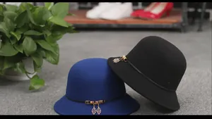 Detail view of wool felt cloche hat with gold leaf charm on dark blue and black fabric