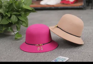 Detail of wool fedora hats in fuchsia and camel with elegant leather strap and leaf charm