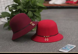 Detail of wool felt cloche hats in wine red and bright red with gold leaf charms