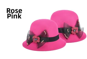 Détail du chapeau cloche en laine rose avec ruban noir et ornements floraux en mesh