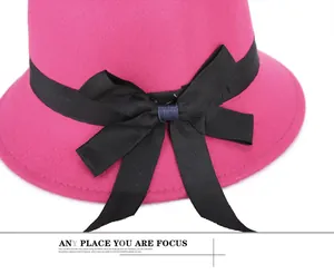 Detail of rose red wool felt cloche hat featuring a decorative black ribbon bow accent