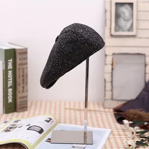 Detail view of grey wool flat cap texture and structure on a minimalist metal stand