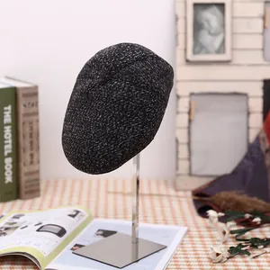 Classic grey tweed flat cap for men displayed on a stand in a warm retro interior