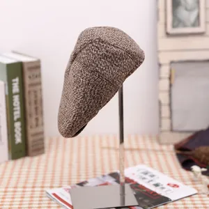Detailed view of a brown tweed flat cap for men displayed on a modern metal hat stand