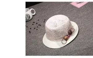 Détail d'un chapeau de soleil en dentelle rose avec fleurs en tissu et perles élégantes