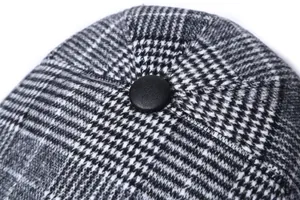 Close-up of wool houndstooth pattern and leather top button on the men flat cap