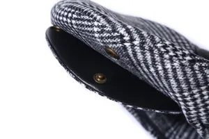 Detailed macro view of the herringbone wool fabric and leather brim with a bronze snap button