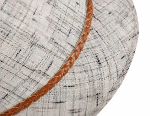 Dettaglio cappello da sole in lino con trama grigia e cinturino in pelle marrone con cuciture