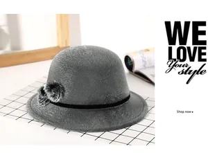 Detail of dark grey faux fur cloche hat with black velvet ribbon and fluffy pom-pom accents