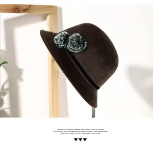 Detailed view of brown wool felt hat featuring stylish faux fur balls with crystal center