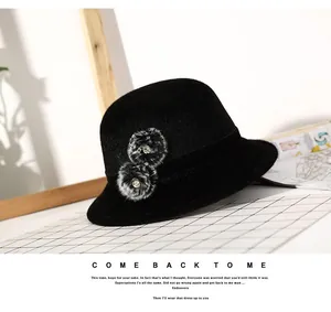 Close-up of black wool bucket hat with grey faux fur pom-poms and rhinestone accents