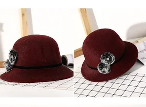 Detail showing burgundy wool cloche hat with black velvet ribbon and faux fur pom-poms