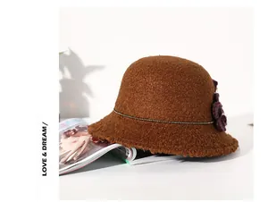 Λεπτομέρεια καφέ γούνινου καπέλου bucket με διακοσμητικό λουλούδι και χρυσή αλυσίδα