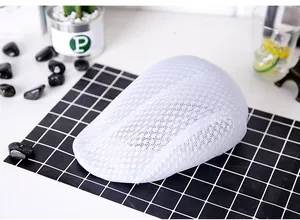 Detail of the white breathable mesh fabric on a summer flat cap for men shown on a table